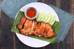 Morceaux de poulet grillé à la marinade thaï servis avec sauce pimentée et concombre